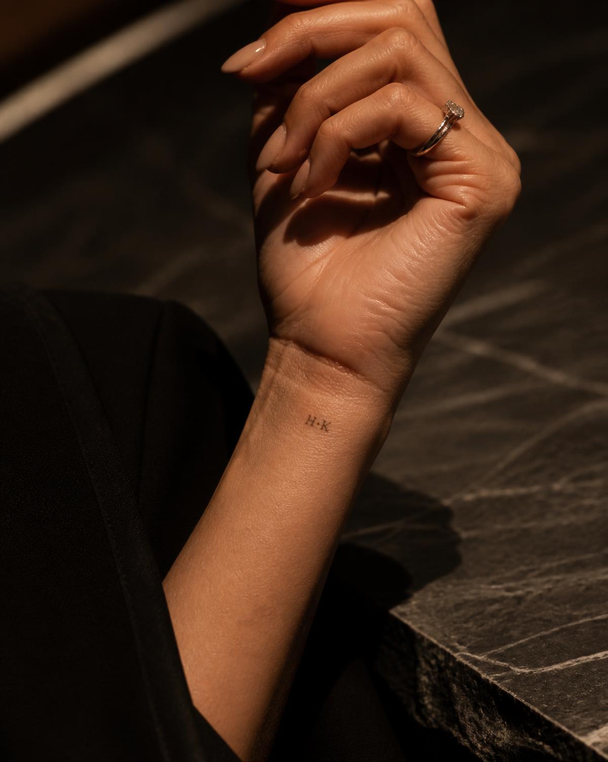 Tatuagem minimalista de iniciais no punho de uma convidada